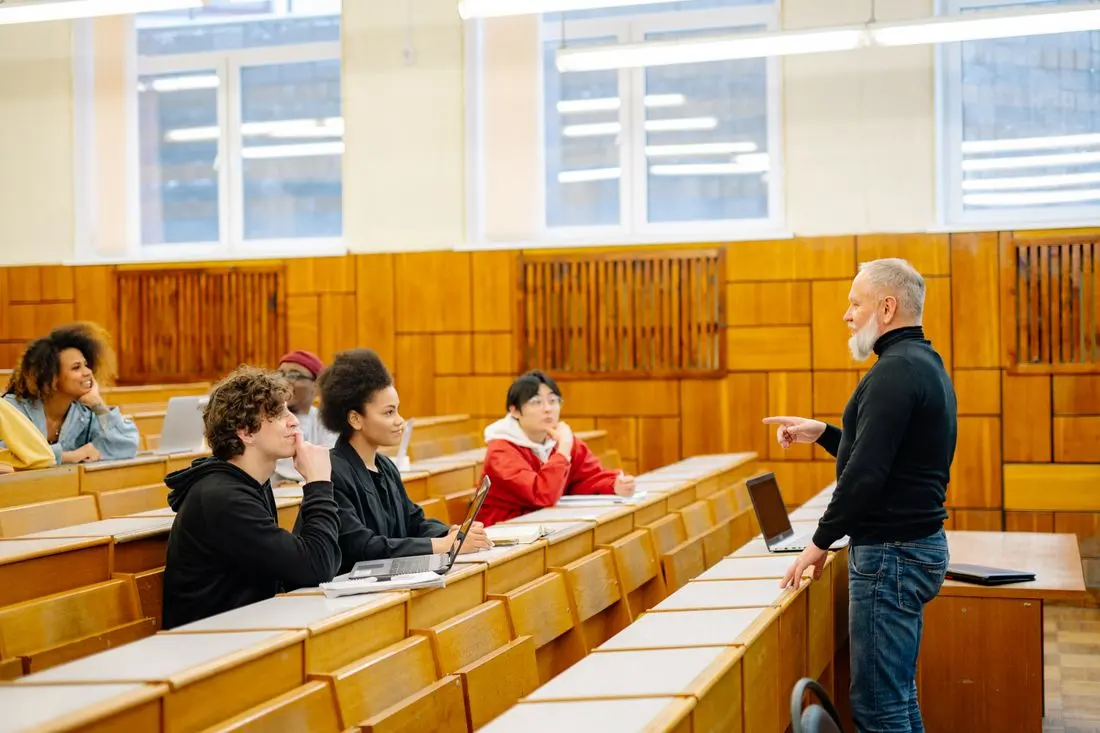 A lecturer talking with students in a lecture hall