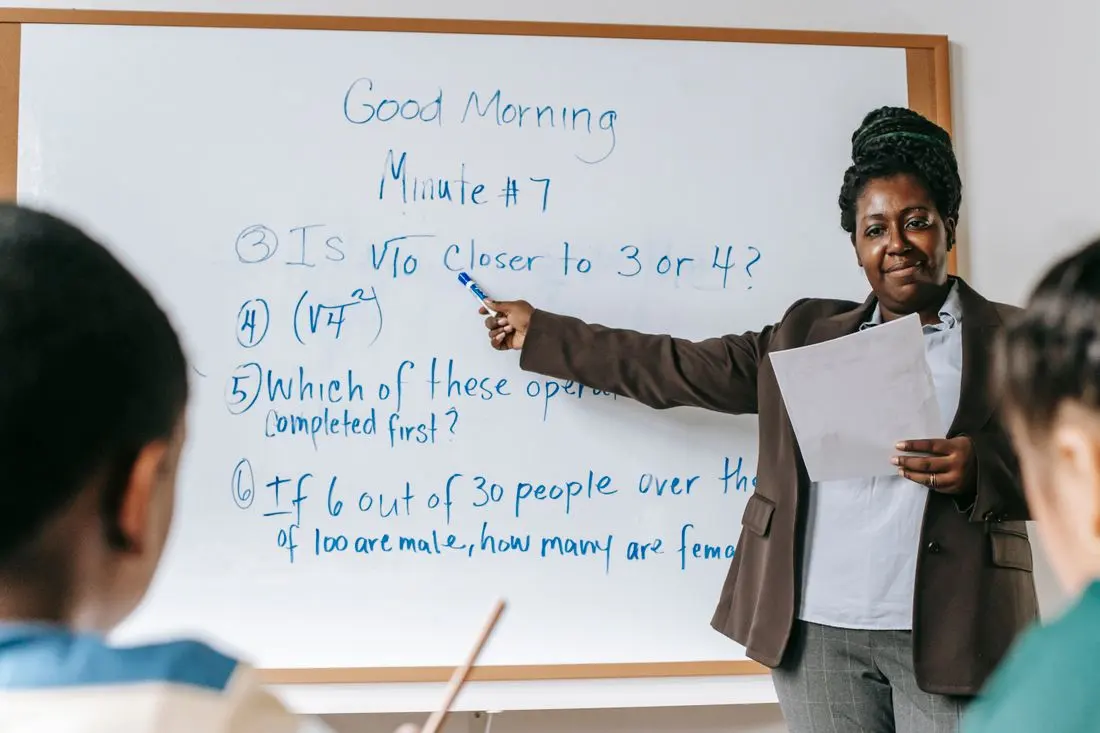 A math teacher pointing at problems on a whiteboard